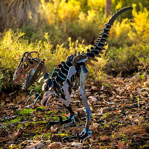 Velociraptor Dinosaur Sculpture Small Metal in Bush Setting
