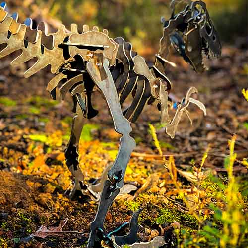 Velociraptor Dinosaur Sculpture Small Metal in Bush Setting Close Up